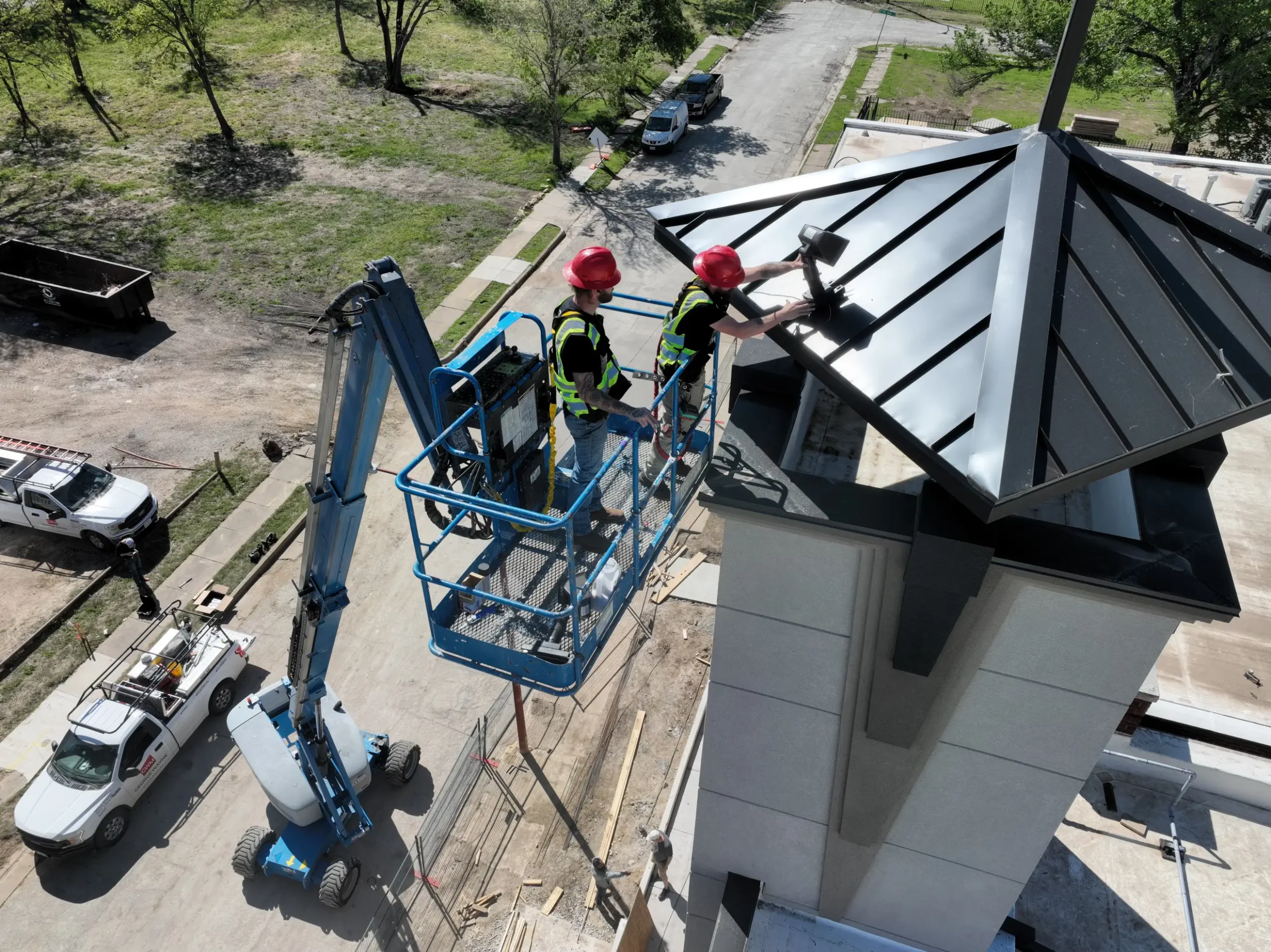 Technicians performing high-access maintenance on a church steeple using a lift.